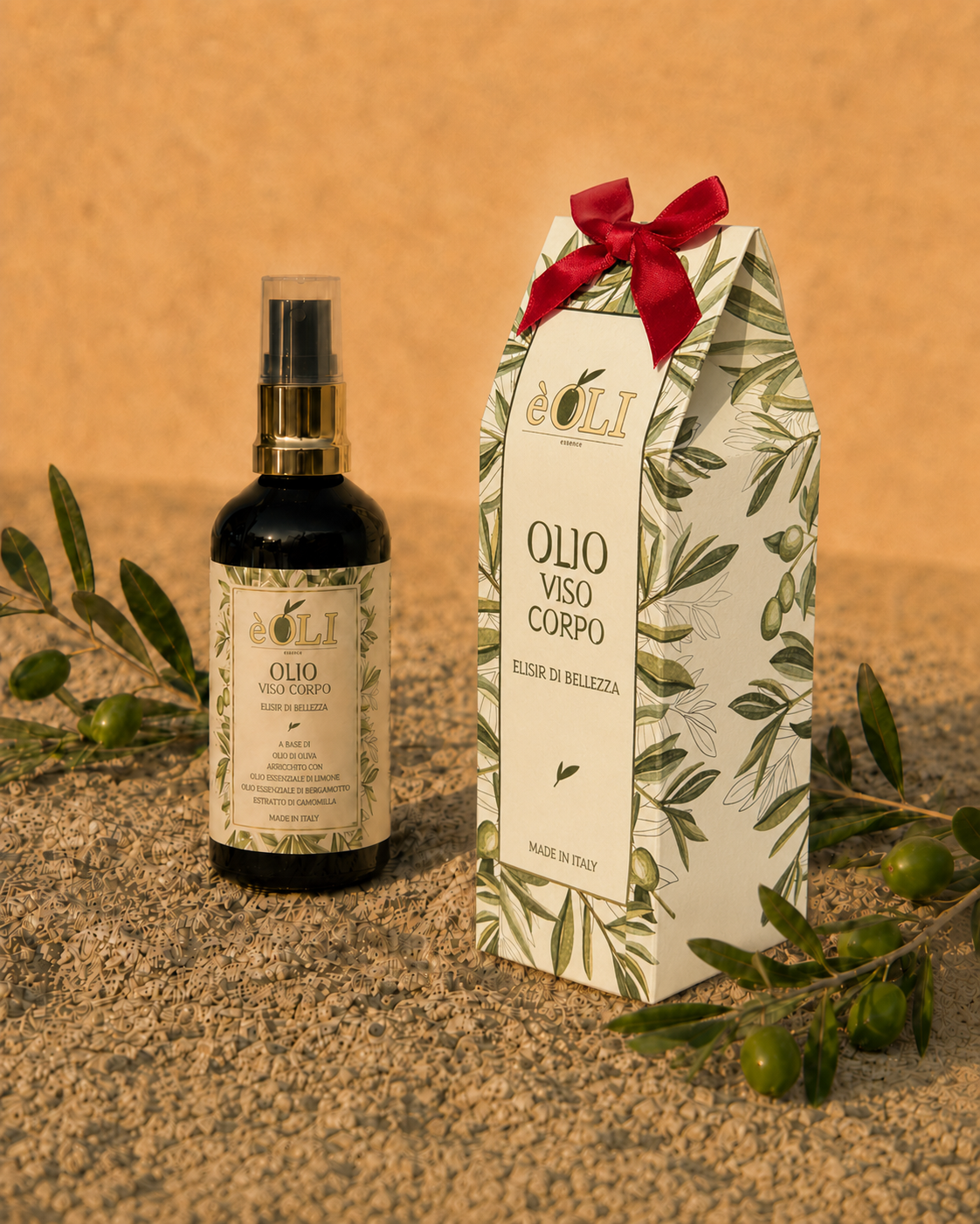Flacone èOLI e packaging con nastro rosso, su sassi toscani con ramo di ulivo